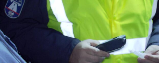 Ein Polizist hält bei einer Verkehrskontrolle ein Alkomat-Messgerät in der Hand.